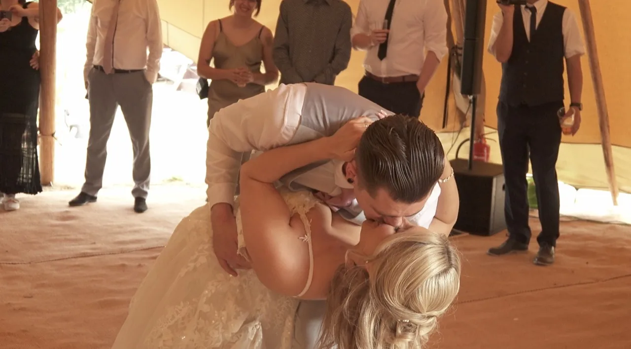 A groom dipping his bride for a kiss during their first dance beneath the tipi